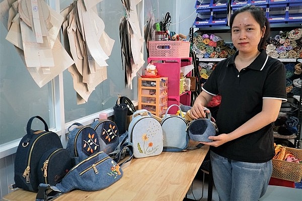 Chị Thắm bên những chiếc túi xách được may từ đồ jeans cũ 