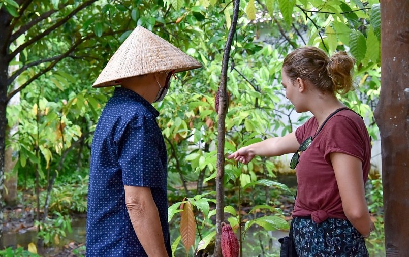 Nữ du khách Camille (phải) nghe ông Lâm Thế Cương giới thiệu về cây ca cao.