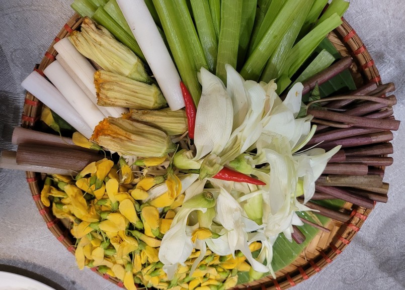 Một đĩa rau đầy sắc màu với rau muống nước tím, bông so đũa, bông điên điển, sen, súng... ăn kèm hợp vị với món cá heo kho lạt hay cá linh.