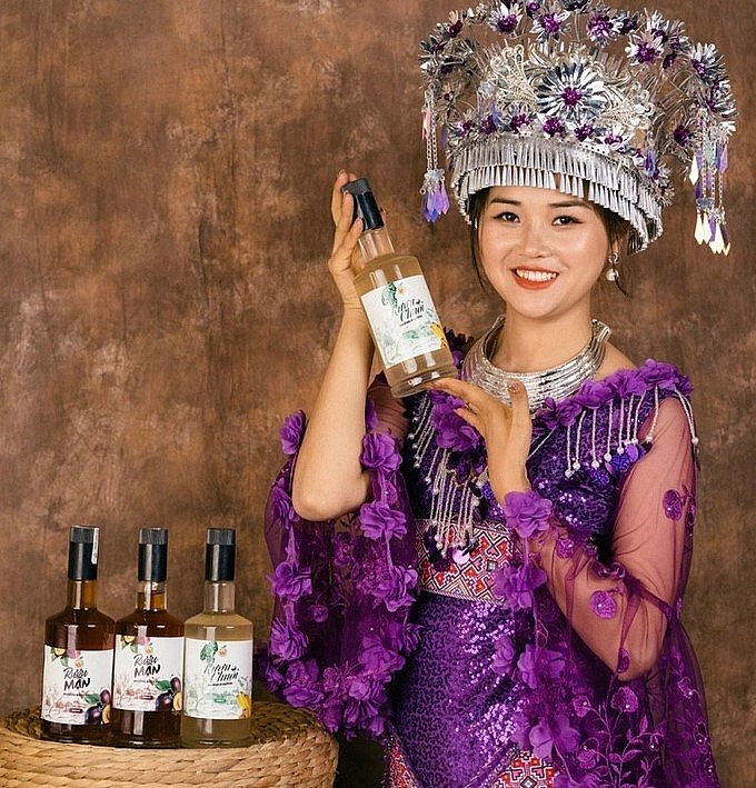 Ma Thị Chú giới thiệu sản phẩm được chế biến sâu làm ra rượu chuối, rượu quýt, rượu mận của HTX. Ảnh: Lưu Hòa.