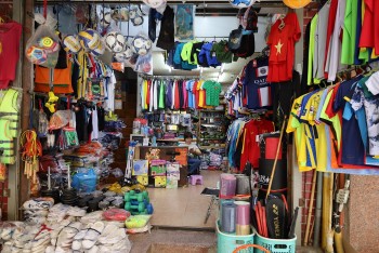 Bán đồ thể thao ăn theo World Cup ế ẩm, chủ tiệm ngồi lướt điện thoại cho qua ngày