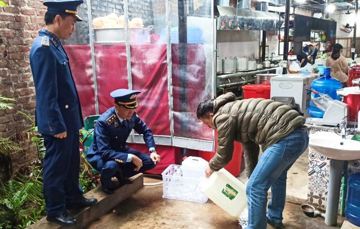 Công chức Đội QLTT số 2 giám sát hộ kinh doanh tiêu huỷ rượu không rõ nguồn gốc.