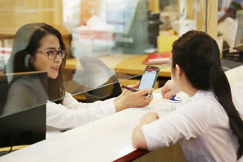 Nhân viên ngân hàng hướng dẫn  hướng dẫn khách hàng sử dụng app ngân hàng điện tử. Ảnh: Phạm Hùng