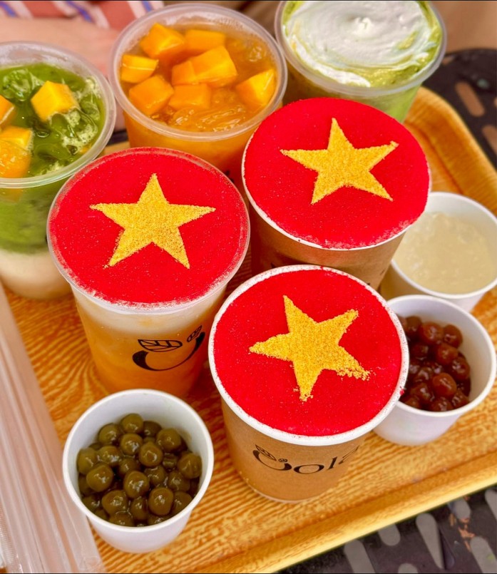 Từ các quán cà phê đường phố đến chuỗi cà phê sang chảnh, giới trẻ đang nô nức rủ nhau check-in với ly nước độc đáo mang đậm màu sắc dân tộc. Những ly matcha, trà sữa, cà phê sữa đá... được khéo léo tạo hình bằng bọt sữa, siro, hoa quả hoặc lớp kem phủ, tái hiện lại lá cờ đỏ rực rỡ với ngôi sao vàng 5 cánh nổi bật.