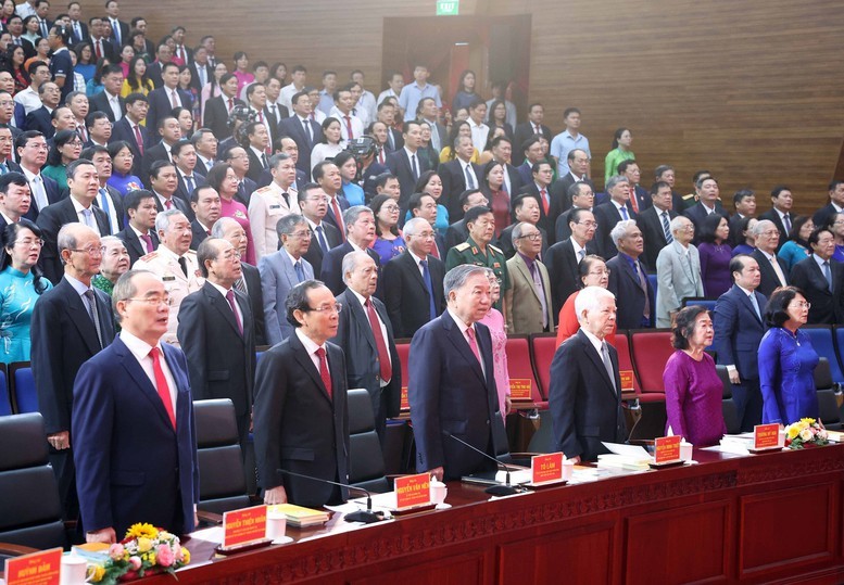 Tổng Bí thư Tô Lâm và các đồng chí lãnh đạo, nguyên lãnh đạo Đảng, Nhà nước thực hiện nghi thức chào cờ tại Lễ Công bố ở điểm cầu TPHCM - Ảnh: TTXVN