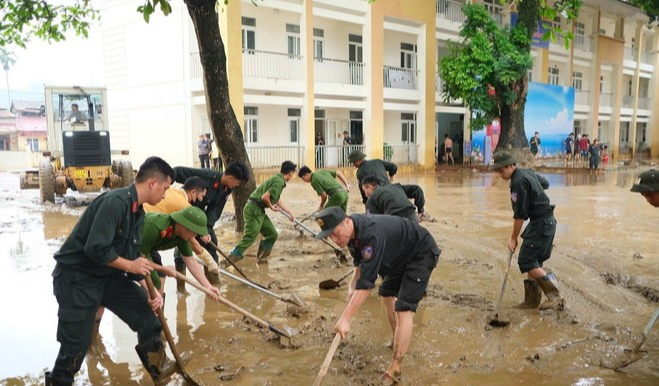 Lực lượng Công an dọn dẹp vệ sinh, bùn đất tại các trường học tại phường Yên Bái. (Ảnh: TTXVN phát)