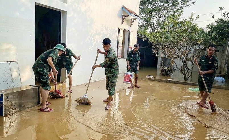Cán bộ chiến sỹ Trung đoàn 95 giúp người dân dọn dẹp khắc phục hậu quả lũ lụt. (Ảnh: TTXVN)