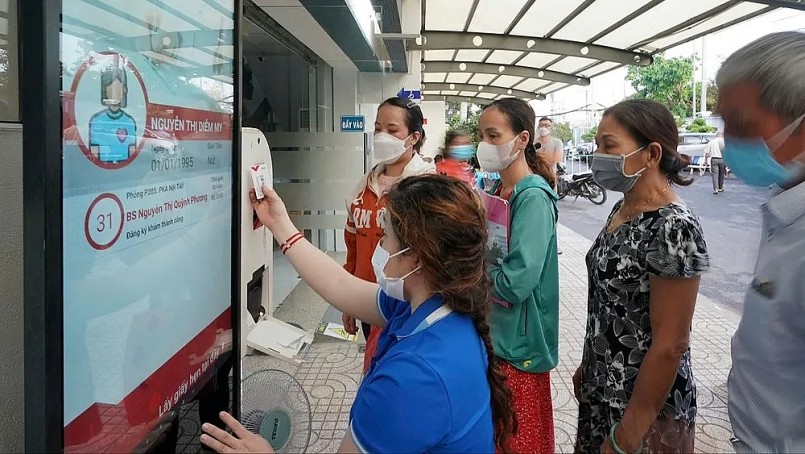 Nhân viên y tế Bệnh viện Thống Nhất TPHCM hướng dẫn người dân quẹt thẻ Tekmedi để đăng ký khám chữa bệnh. Ảnh: HOÀNG HÙNG