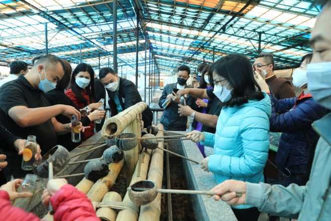 Du khách thích thú với trải nghiệm xin nước từ giếng Vua. Ảnh: Hoàng Hiếu - TTXVN