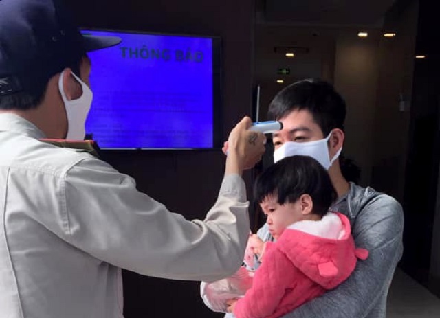 Cư d&acirc;n được kiểm tra th&acirc;n nhiệt khi ra v&agrave;o c&aacute;c to&agrave; nh&agrave;.