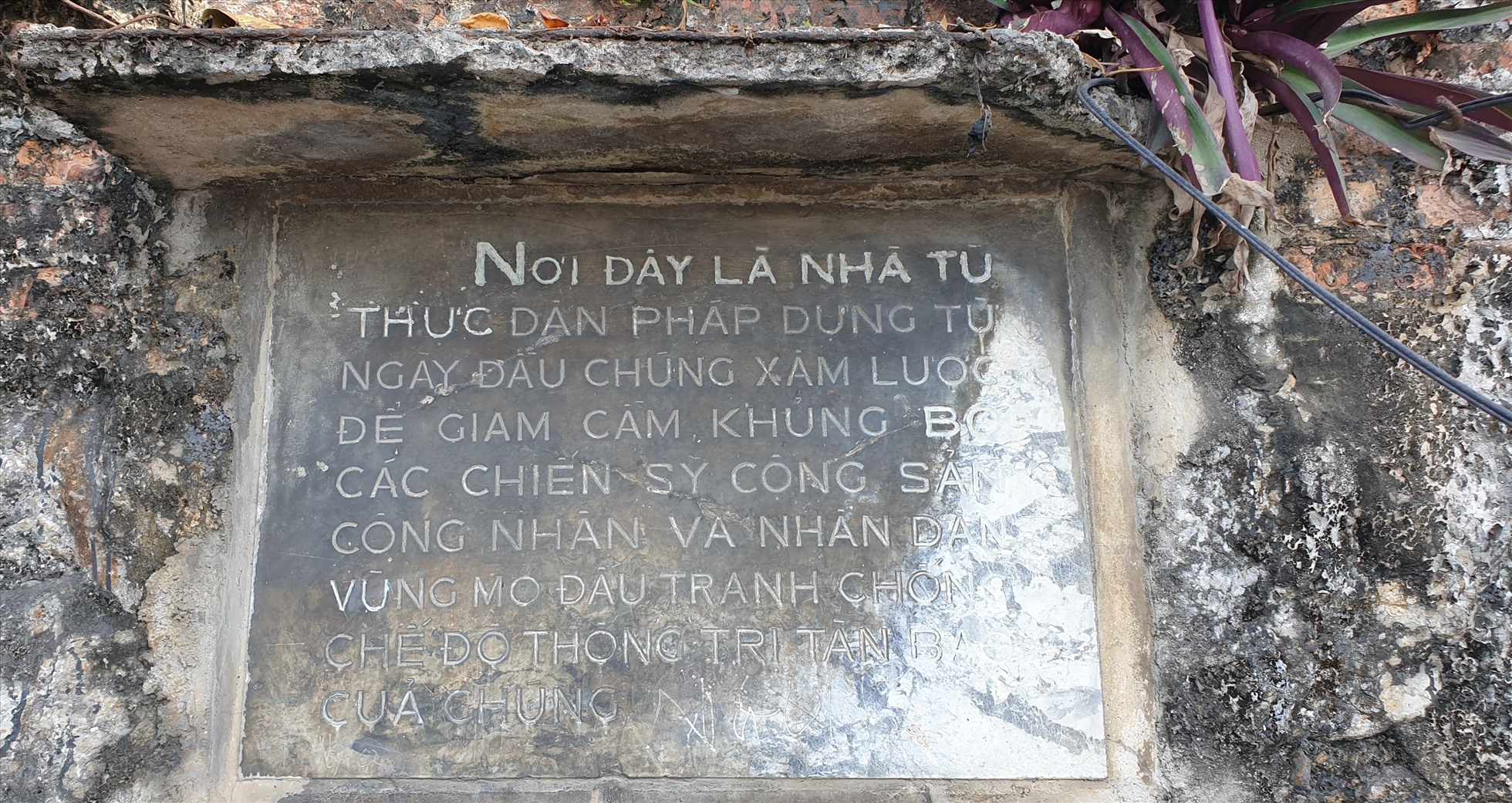 Trên bức tường còn lại của nhà giam có gắn hai tấm bia bằng đá với cùng nội dung. Một bia dựng năm 1963, bia này cao 50cm, rộng 60cm, nội dung của bia như sau: “Nơi đây là nhà tù thực dân Pháp dựng từ ngày đầu chúng xâm lược để giam cầm, khủng bố các chiến sĩ cộng sản, công nhân và nhân dân vùng mỏ đấu tranh chống chế độ thống trị tàn bạo của chúng”. Ảnh: Nguyễn Hùng